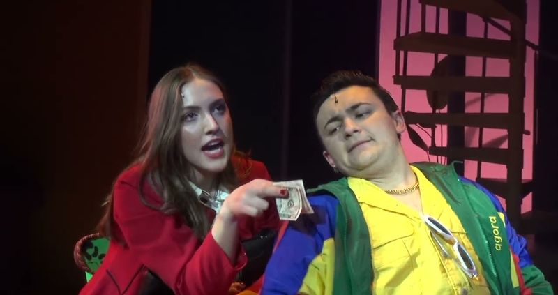 Two characters side by side, one in a red coat holding out a banknote to the other in a color-blocked jacket