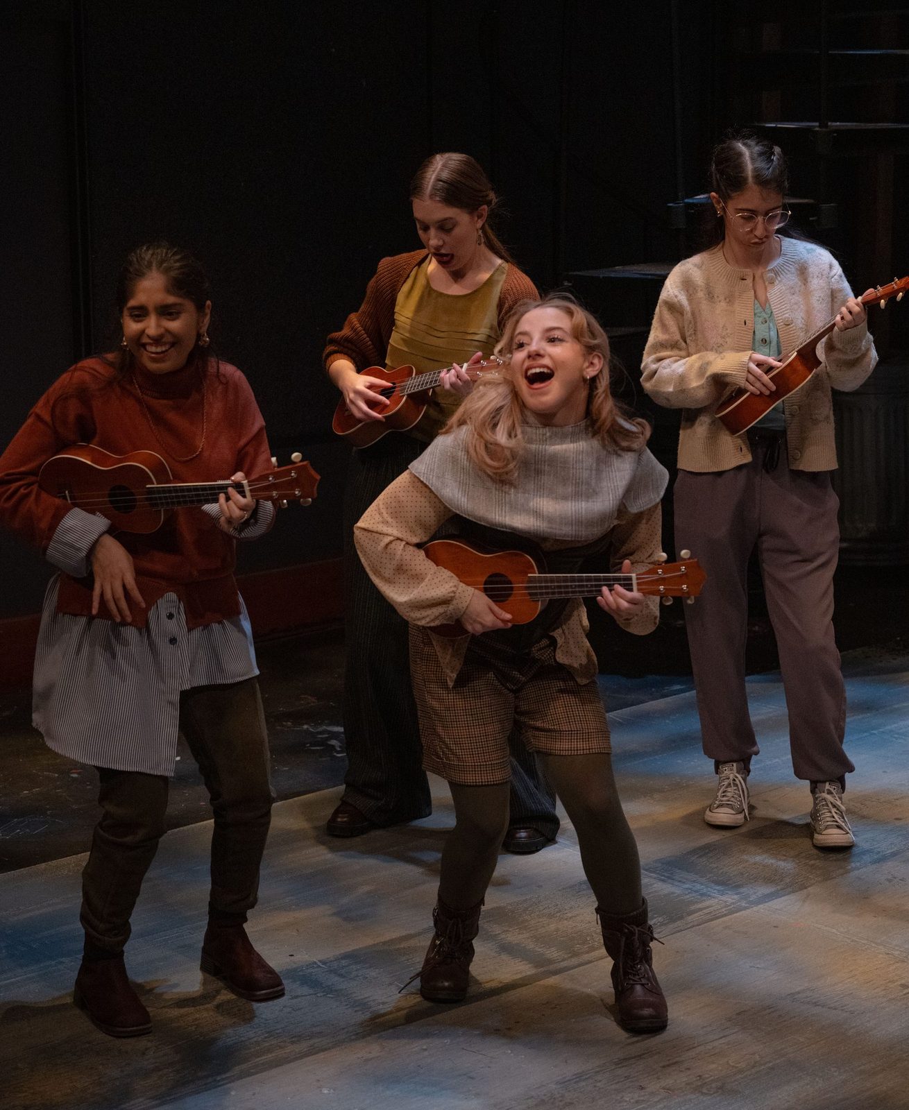 The on-stage ukulele band playing in warm light
