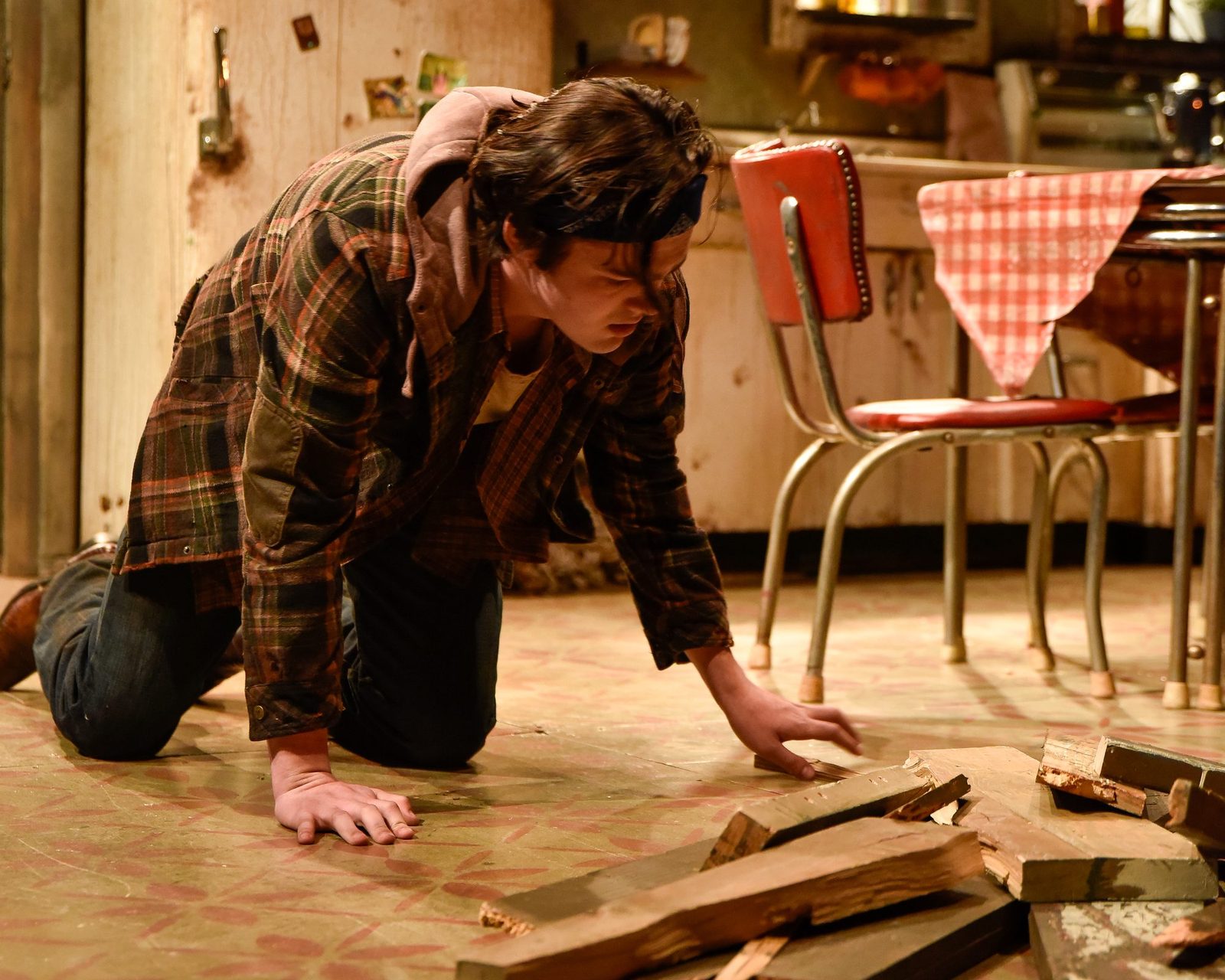 A character kneeling among the wreckage of the broken door
