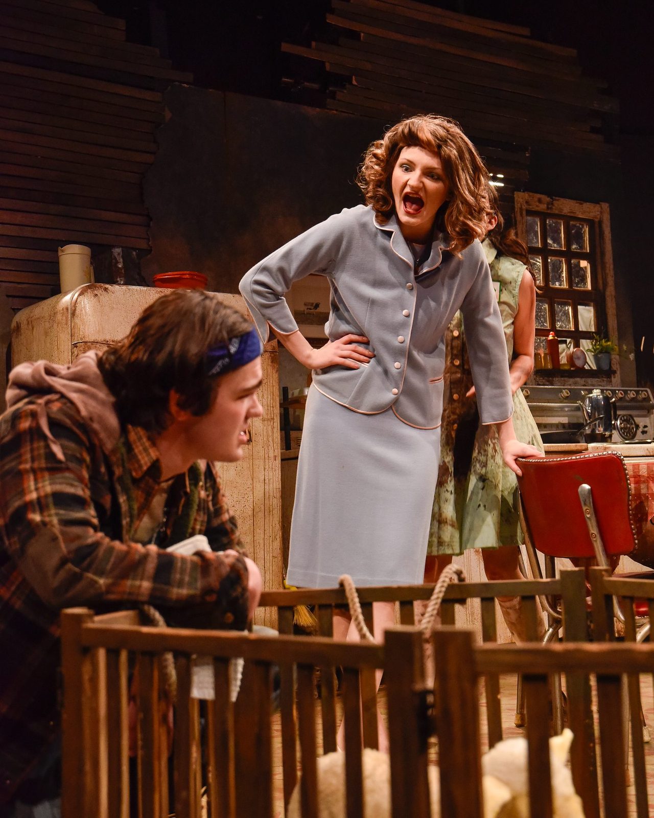 Two characters arguing across the lamb pen on stage