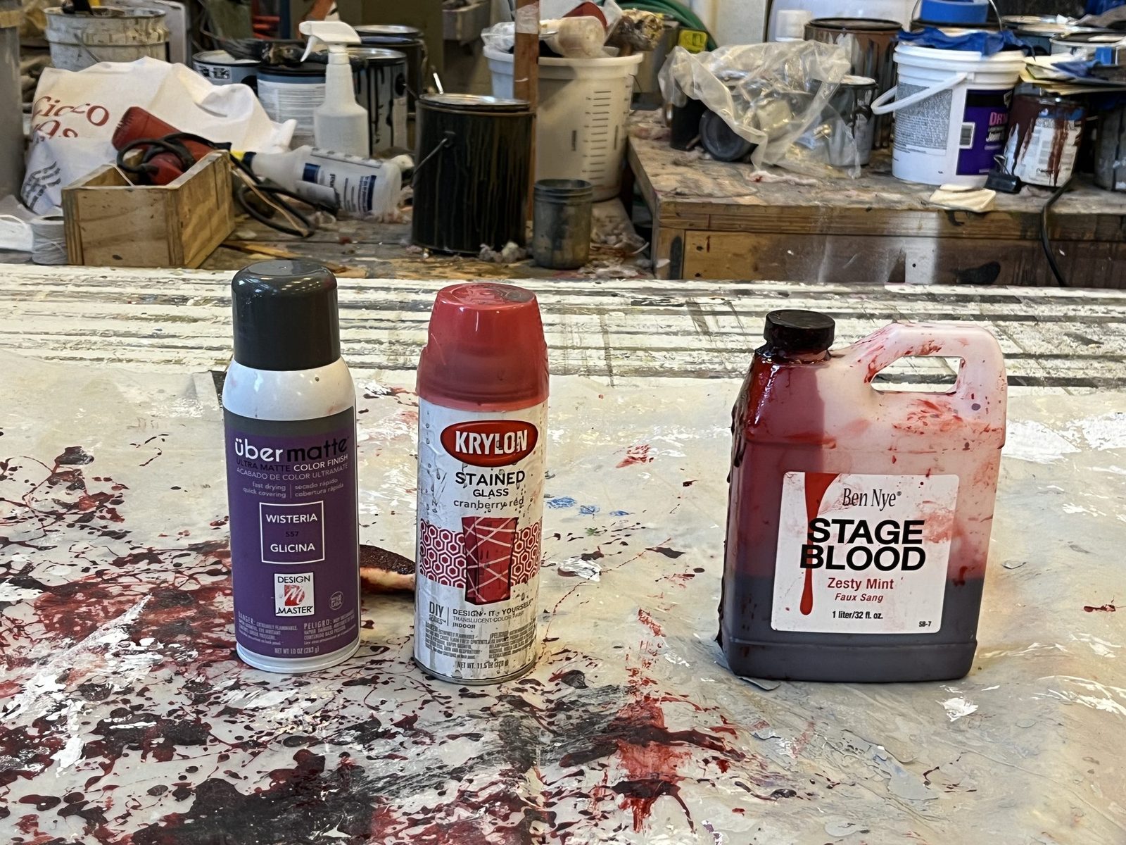 Bottles of stage blood and spray paint on a spattered shop floor