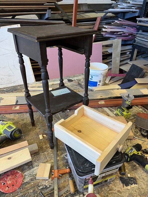 The side table drawer under construction on the bench beside the finished table