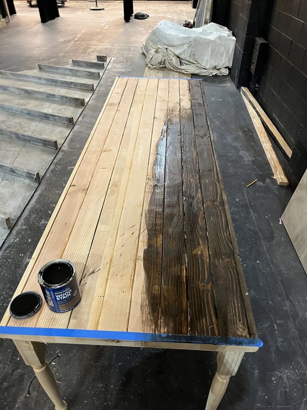 Staining the table top, half finished, masked off at the edges